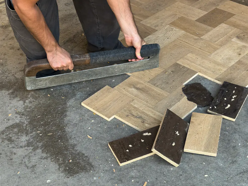 Verlijmde eiken parketblokken in visgraat worden losgemaakt, met oude lijm aan de onderkant
